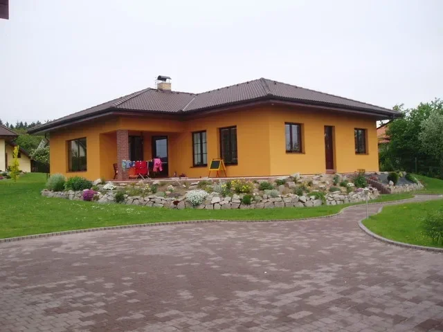 Rodinný dům IRIS s oranžovou fasádou, kamennou skalkou a dlážděným nádvořím