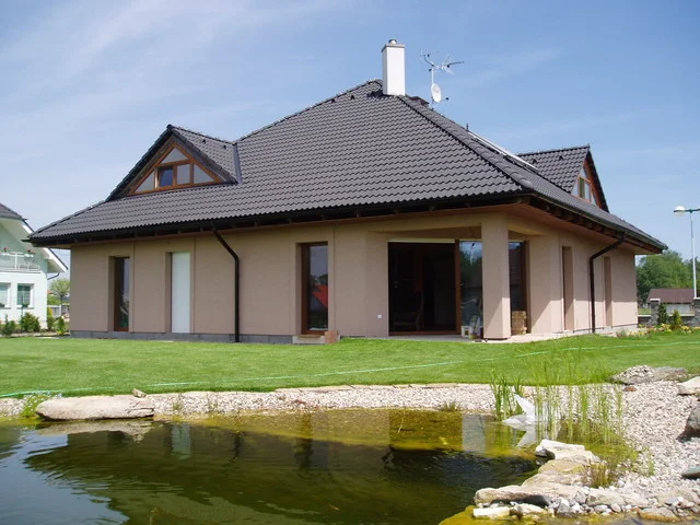 Dům JUPITER s béžovou fasádou a přírodním jezírkem v zahradě
