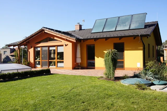 Realizovaný dům MINERVA II s oranžovou fasádou a solárními panely na střeše