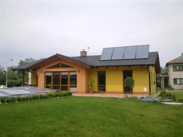 MINERVA II ze zahrady pod zataženou oblohou, žlutá fasáda a terasa