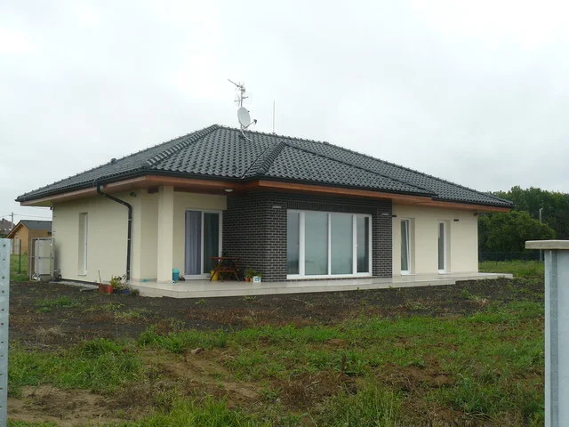 Realizovaný bungalov MINERVA s valbovou střechou, prosklením a terasou před dokončením zahrady