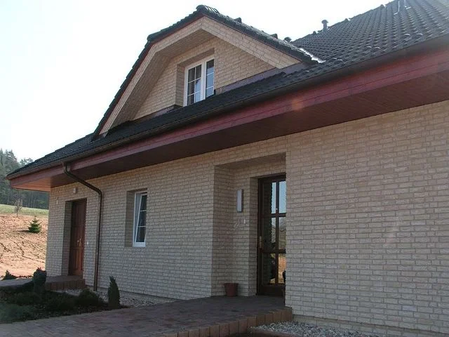 Realizovaný dům FORTUNA s fasádou ze světlých lícových cihel a vikýřem