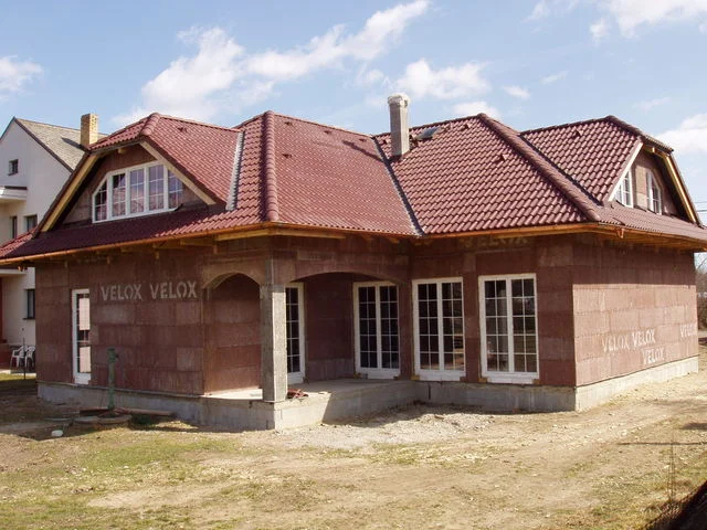 Rozestavěný dům FORTUNA s červenou krytinou a neomítnutými stěnami VELOX