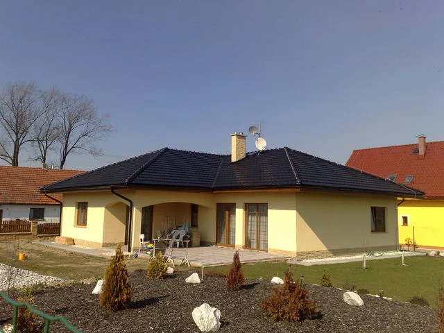 Bungalov AFRODITE se žlutou fasádou, černou valbovou střechou a krytou terasou