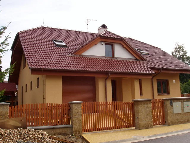 Dokončený dům HERA s okrovou fasádou a červenou střechou od ulice