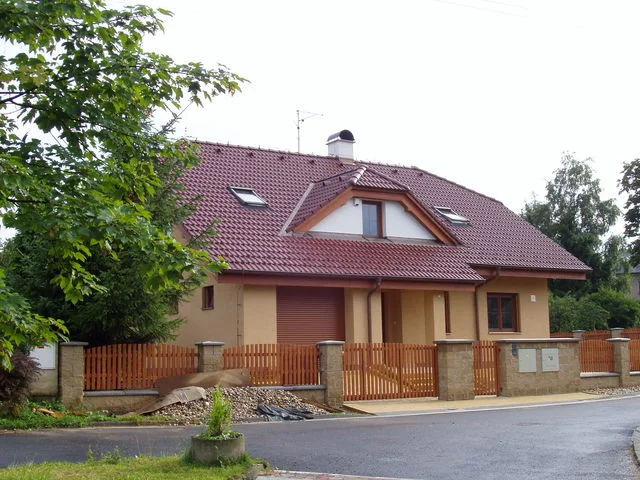 Realizovaný dům HERA od nároží ulice s garáží a vzrostlými stromy