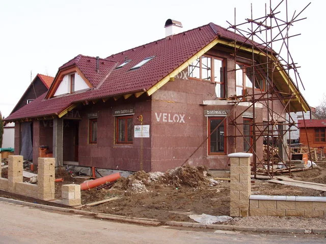 Stavba domu HERA z panelů VELOX s hotovou střechou a lešením u nároží