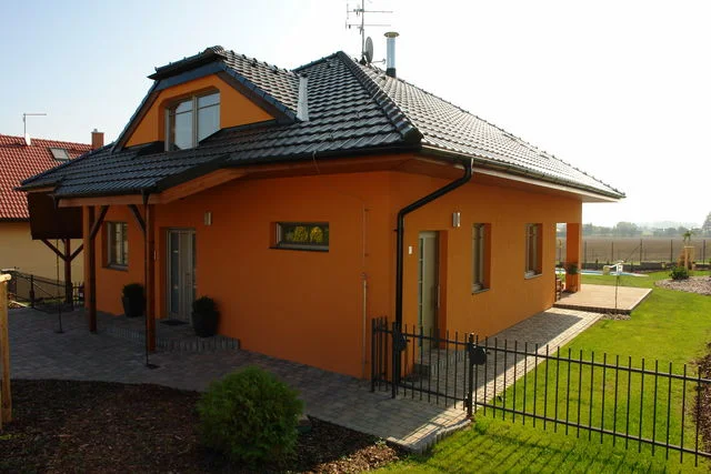 Realizovaný dům Charis s oranžovou fasádou, vikýřem a krytým vstupem