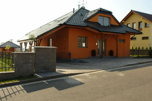 Dům Charis s oranžovou fasádou od ulice, zděné sloupky vjezdu
