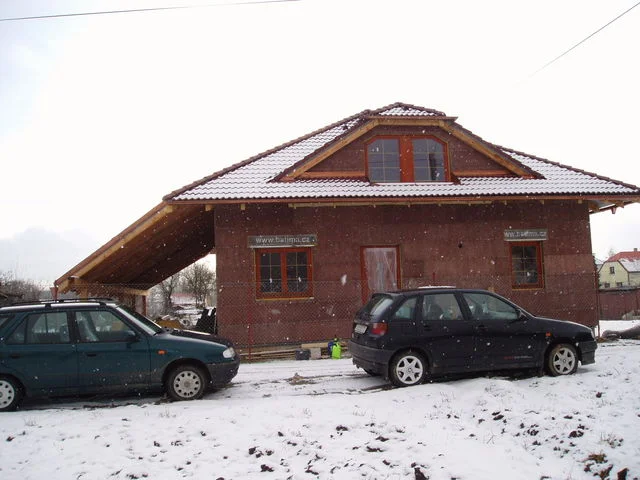 Sněžení nad rozestavěným domem Charis, dva zaparkované automobily před stavbou