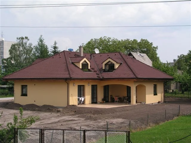 Dům AFRODITE se žlutou fasádou a krytou terasou, terén před dokončením