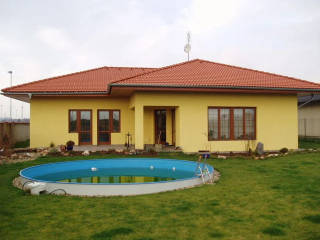 Zahradní strana žlutého bungalovu IRIS s kruhovým nadzemním bazénem