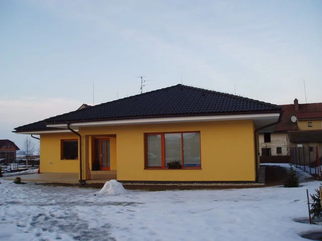 Žlutý bungalov IRIS v zimě, zasněžený pozemek a krytý vstup
