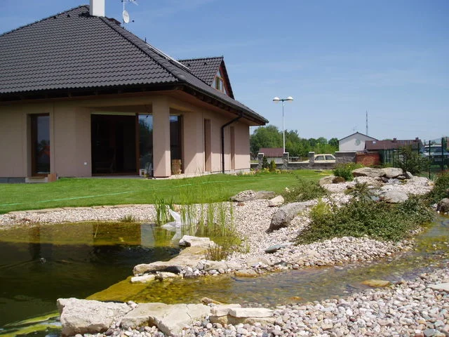 Detail krytého sezení domu Jupiter u přírodního jezírka s kamenným břehem