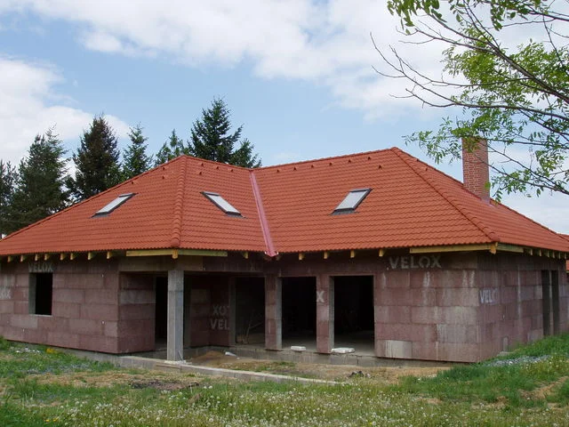 Rozestavěný dům AFRODITE s hotovou červenou valbovou střechou a stěnami VELOX