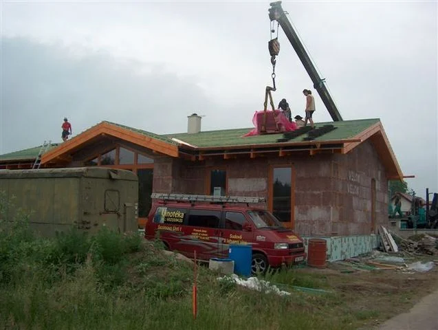 Jeřáb vynáší materiál na střechu stavby Minerva II, dělníci na bednění