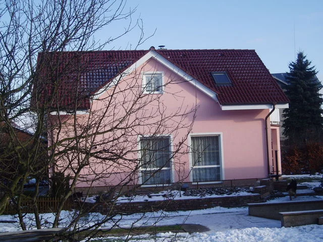 Zahradní strana růžového domu Mini se zasněženým chodníkem a holými stromy