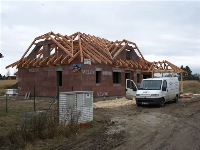 Rodinný dům NIKÉ ve fázi montáže krovu, před domem dodávka firmy