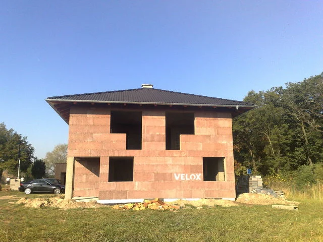 Rozestavěný dům Prima z panelů VELOX se stavebním materiálem u paty stěny