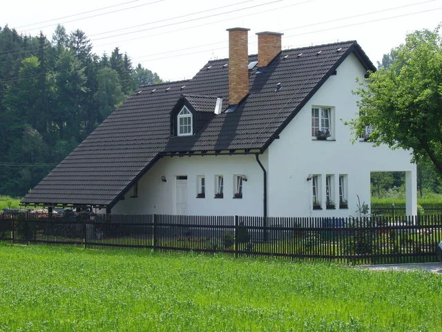 Rodinný dům VENUS s bílou fasádou a hnědou sedlovou střechou u lesa