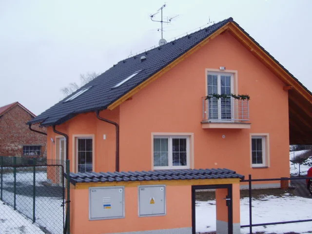 Dům VERONIKA s oranžovou fasádou a francouzským balkonem v zimě