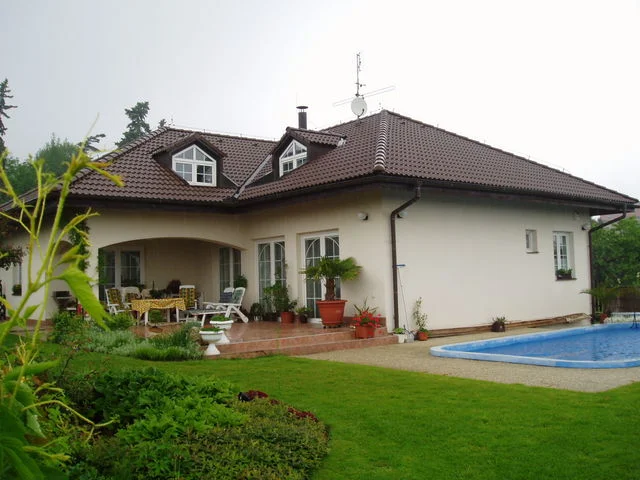 Dokončený dům AFRODITE 1 s krémovou fasádou, krytou terasou a bazénem