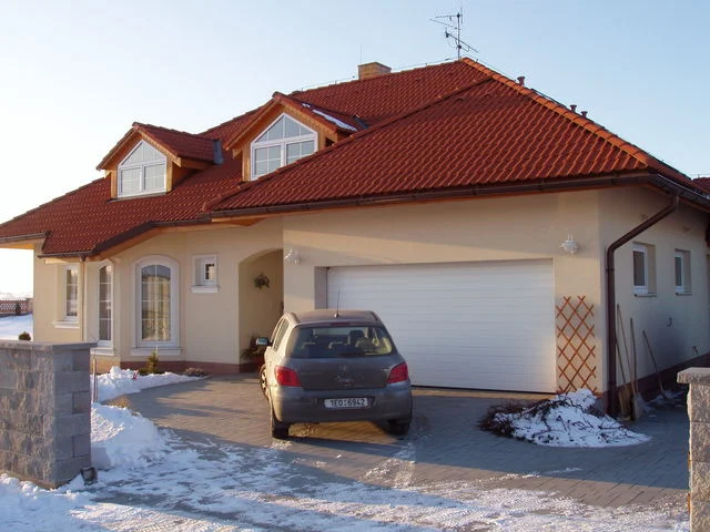 Vjezd k domu AFRODITE s garáží a zaparkovaným autem v zimě