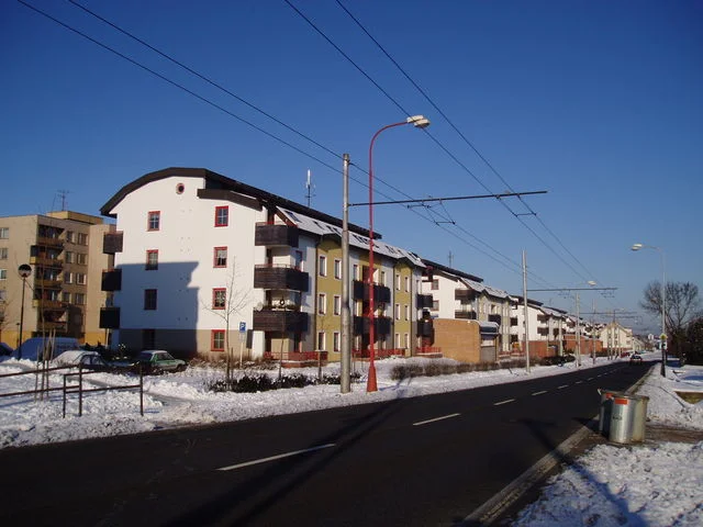 Bytové domy v Hradci Králové podél zasněžené ulice s trolejemi