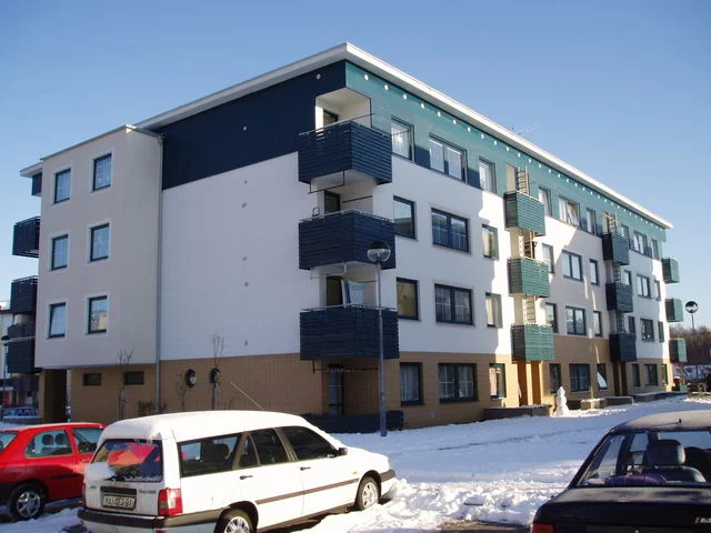 Bytový dům s tmavými balkony a zaparkovanými auty v zimě