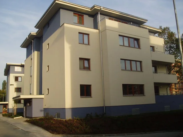 Dokončený bytový dům v Malešicích s krémovou a modrou fasádou