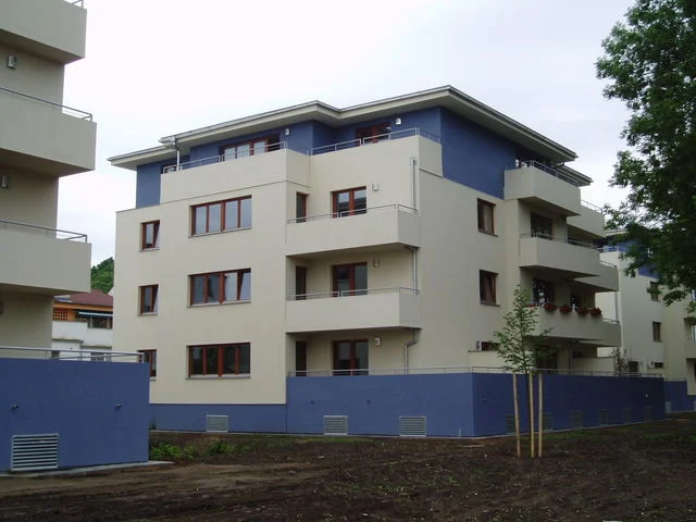 Bytový dům s modrými akcenty na fasádě, terén před dokončením úprav