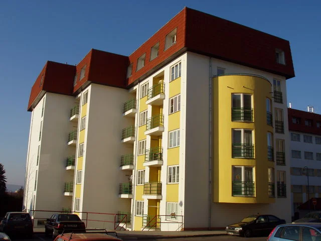 Nároží bytového domu Větrník s oblým žlutým rizalitem a balkony