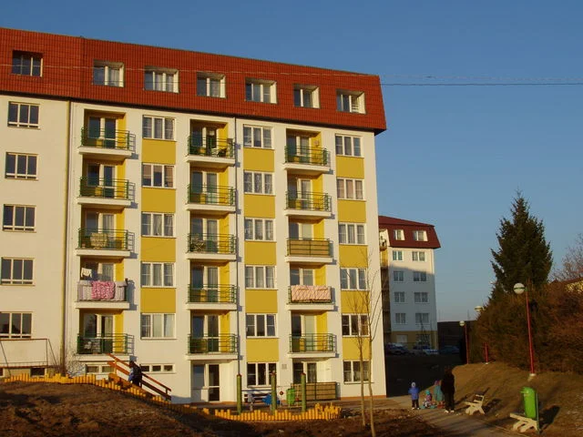 Bytový dům Větrník s balkony a dětským hřištěm ve večerním slunci