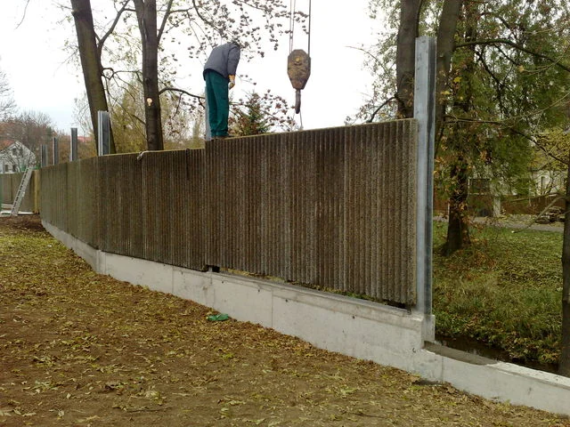 Pracovník na hotové části protihlukové stěny s betonovým základovým prahem