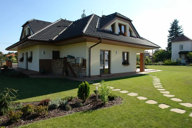 Rodinný dům FORTUNA ze zahrady s kamennými šlapáky v trávníku