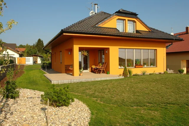 Dům CHARIS s okrovou fasádou, krytou terasou a upravenou zahradou